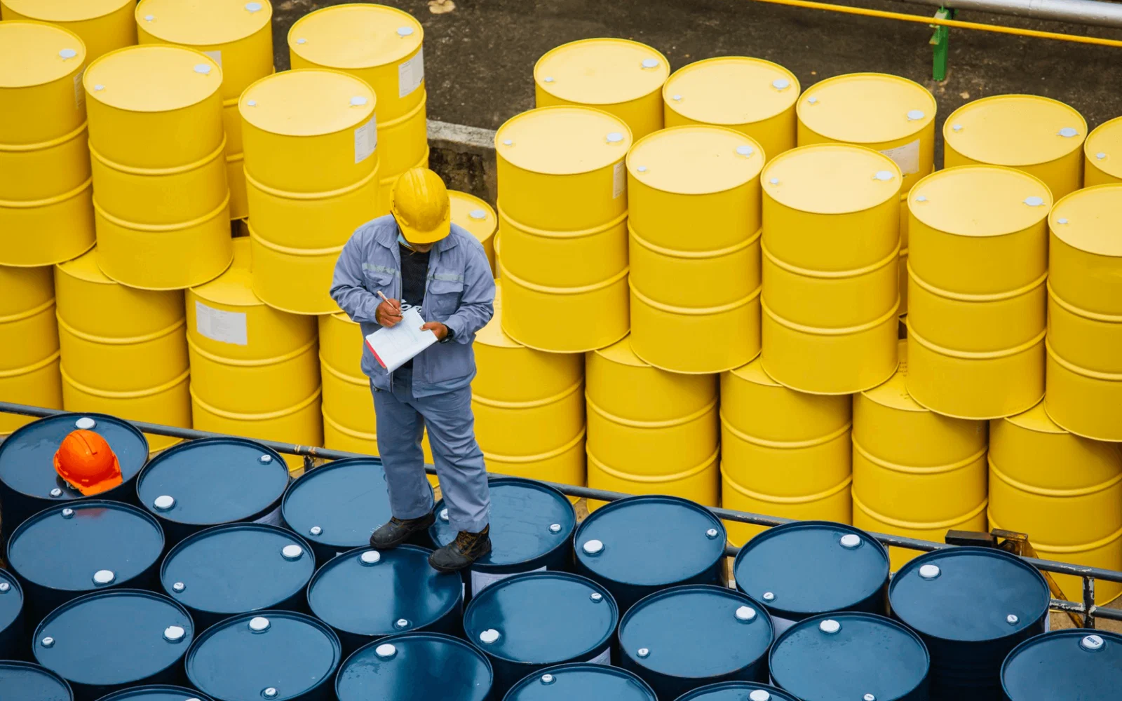 Worker inspecting stacked oil barrels